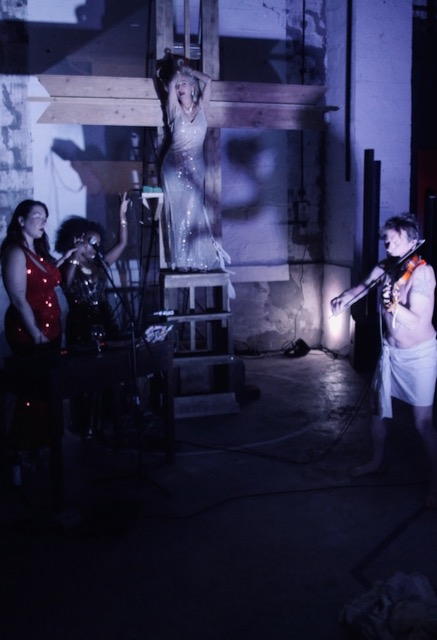 Performance artistique contemporaine — Marilyn’Project aux Glacières de la banlieue, avec Bagheera Poulin interprétant Marilyn Monroe sur une structure en bois et Paul Lazar au violon